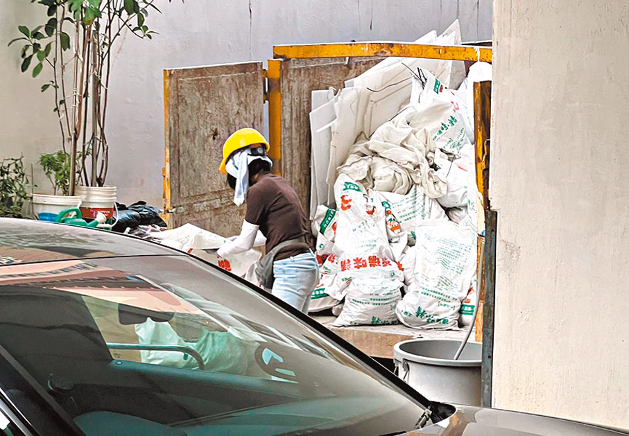 ●女工將棚網和發泡膠推往垃圾斗棄置。