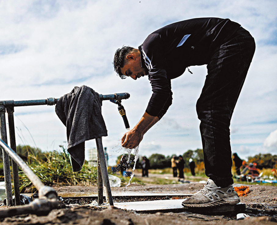 ●一名敘利亞難民在法國北部敦克爾克附近一處臨時營地洗臉。 法新社