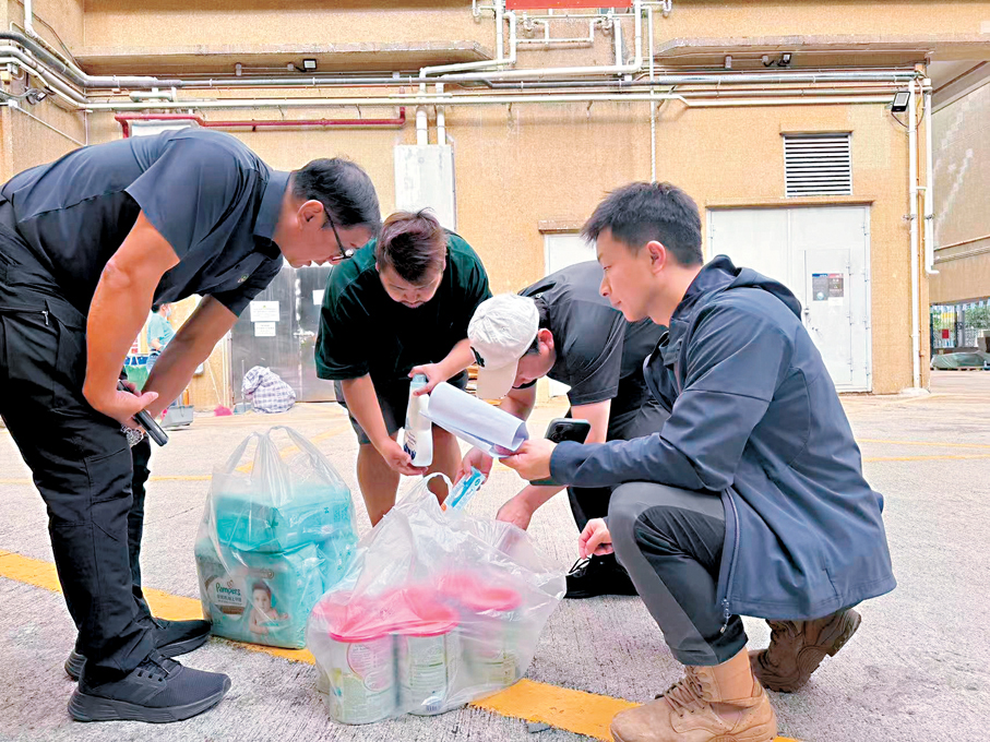 ●來自內地的藍天救援隊成員為一名大埔受災災民派發嬰兒尿布及奶粉等物資。這名受災的父親現時帶着1歲半和3歲的兩個女兒在安置點居住。