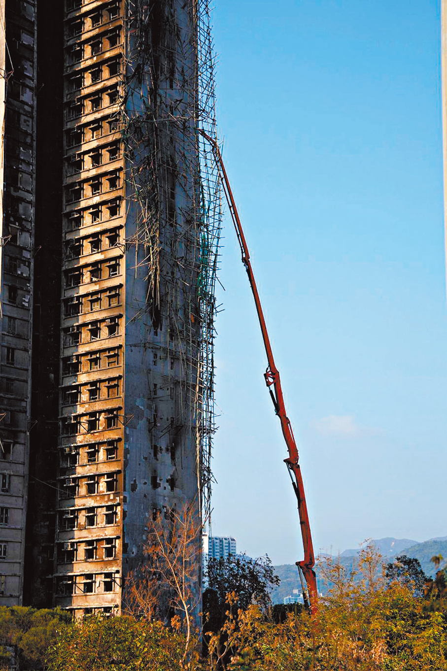 ●吊臂車升起吊臂小心協助工人拆除外牆的棚架及棚網。 香港文匯報記者黃宇威  攝
