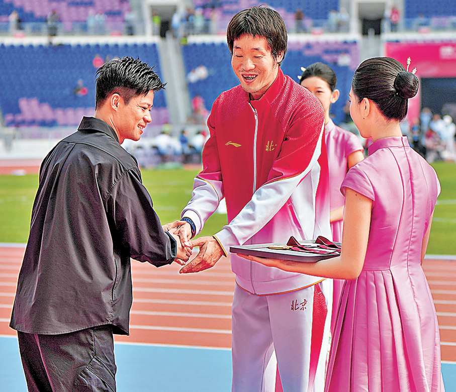 ●蘇炳添（左一）與北京隊跳遠選手張鑫樂（左二）握手。 新華社