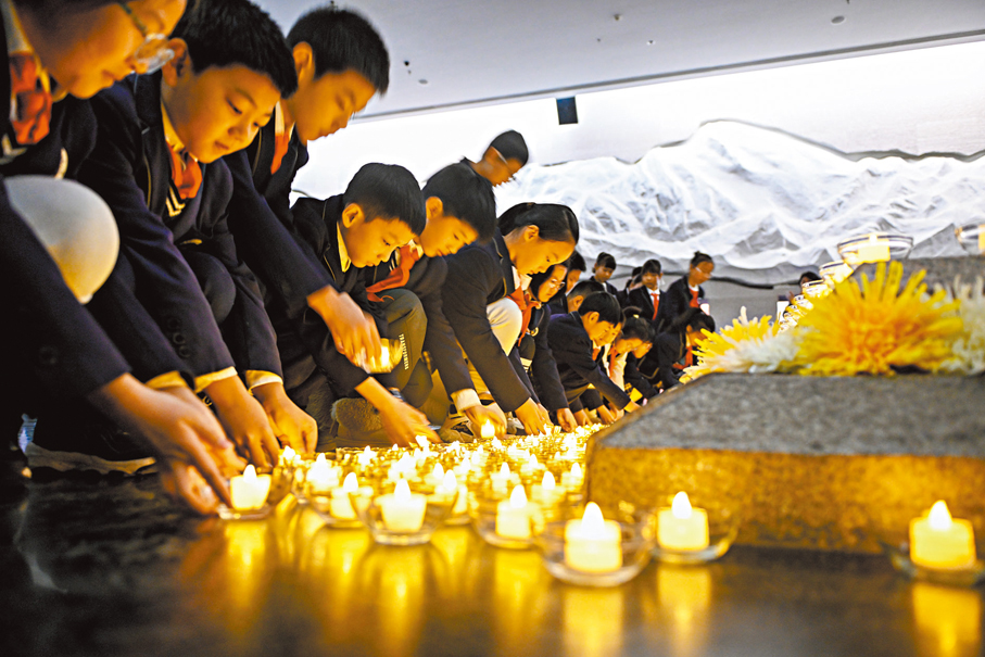 ●瀋陽「九·一八」歷史博物館序廳內，參與公祭日悼念活動的學生將蠟燭置於臥碑前。 中新社