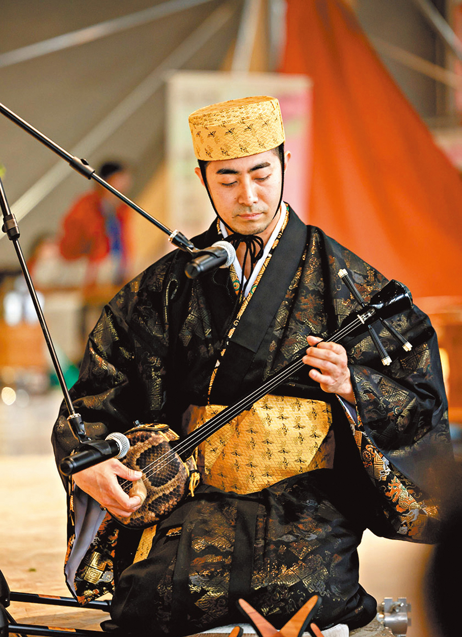 ●西原圭佑穿着琉球傳統服飾彈奏傳統民族樂器三線，展示琉球傳統文化。香港文匯報北京傳真