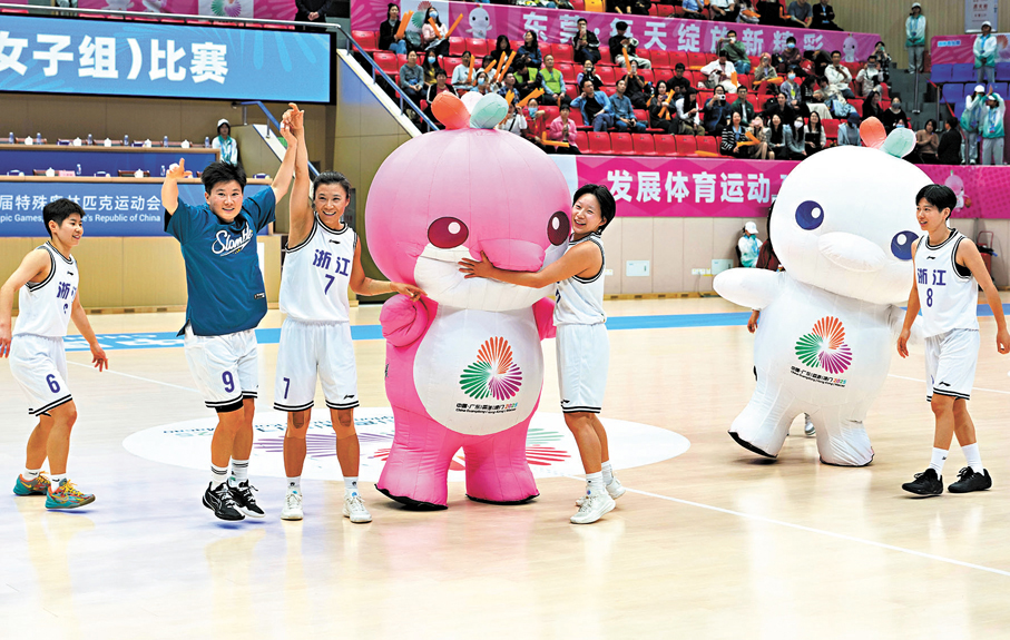●12月11日，浙江隊球員和吉祥物「樂融融」「喜洋洋」互動。當日，在廣東東莞舉行的全國第十二屆殘疾人運動會暨第九屆特殊奧林匹克運動會聾人籃球比賽女子組小組賽A組比賽中，浙江隊132比35戰勝河北隊。     新華社