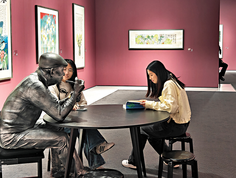 ●觀眾坐在「黃永玉」雕塑前假裝與之交流探討藝術問題。