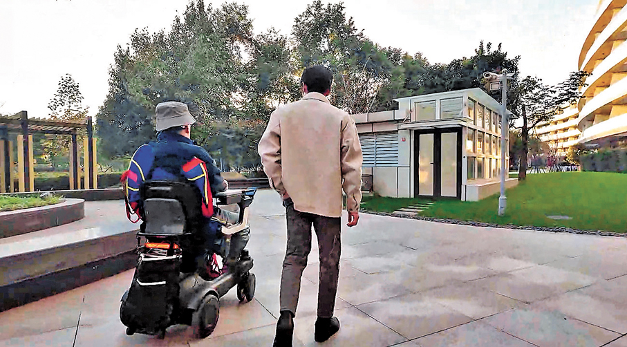 ●四肢癱瘓患者（左）通過腦智卓越中心等單位研發的腦機接口系統意念控制輪椅在小區自如散步。