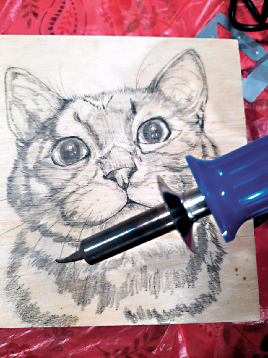 ●鍾杏珠用辣雞(燒焊槍)作畫筆，在木板上雕刻。