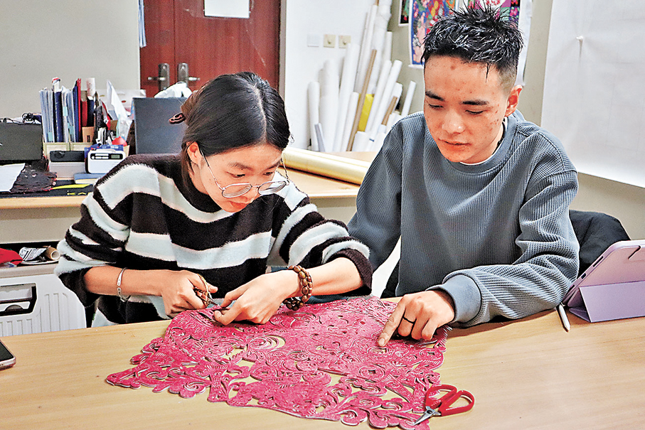 ●熊若雨（左）與賀強交流剪紙技藝。 中新社