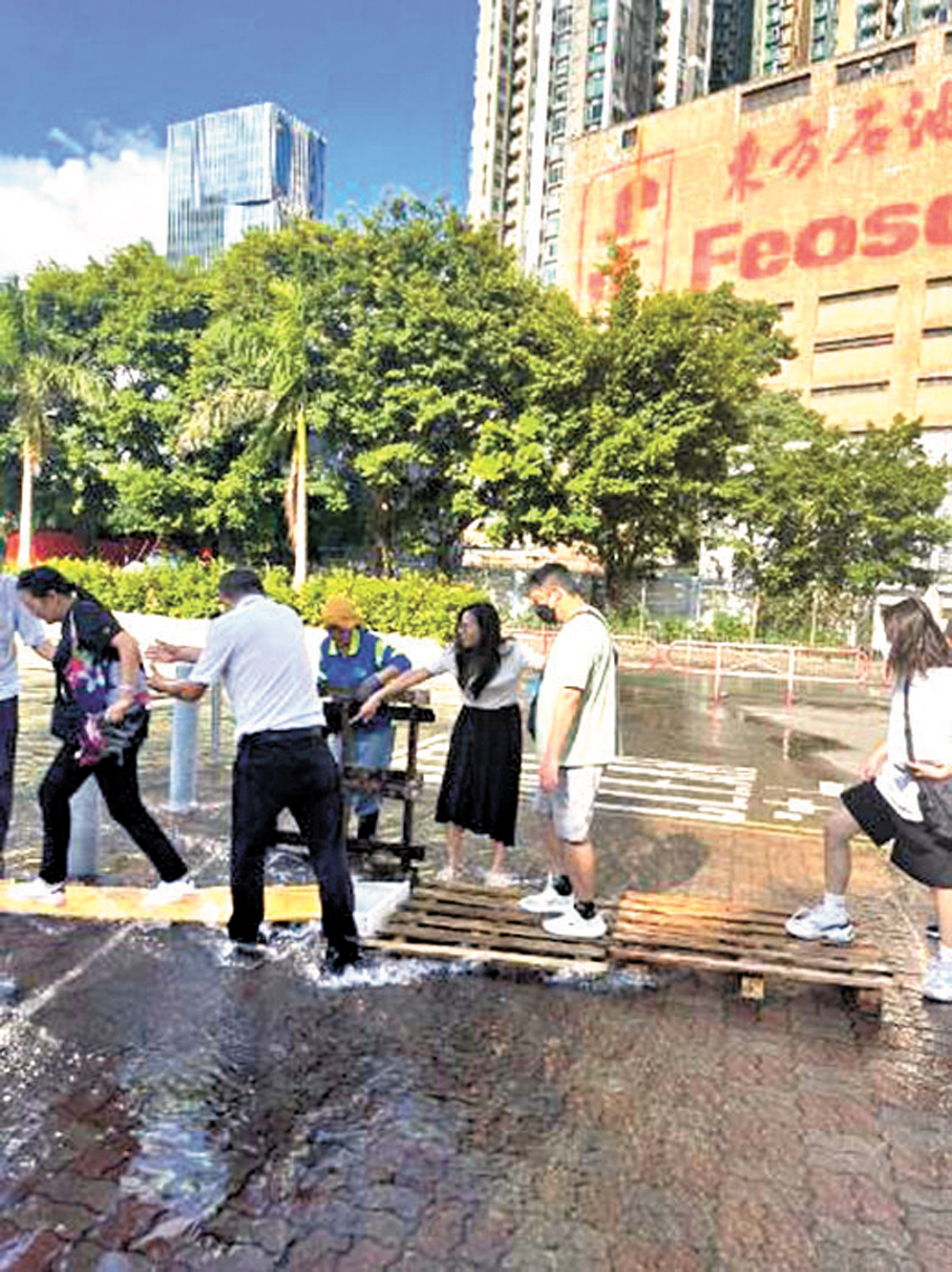●海麗邨鹹水管爆裂，行人路嚴重水浸，荔枝角南小區關愛隊義工協助居民安全過馬路。 作者供圖