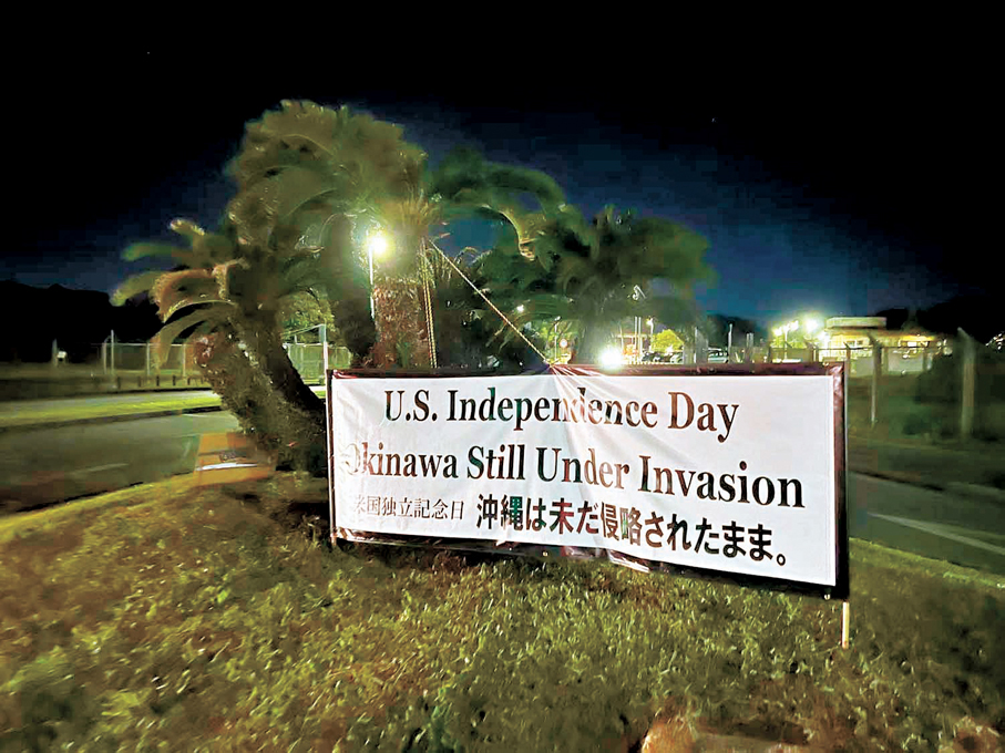 ●2025年7月4日美國國慶節，在沖繩嘉手納美軍基地外，一張橫幅寫道：美國在慶祝獨立日，沖繩卻依然處於被侵略中。資料圖片