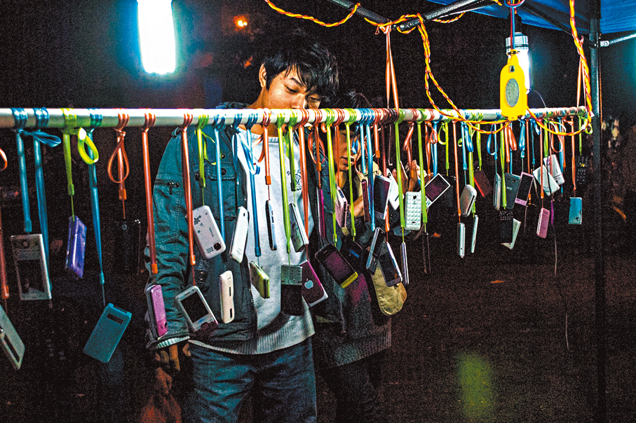 ●二○一二年一月一日，東莞。山寨手機流行，晚上下班後，打工人在夜市的小攤上選購手機。