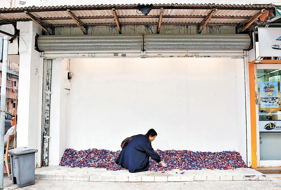 ●路人拾起位於大坑區街角的糖果。 卓納畫廊供圖