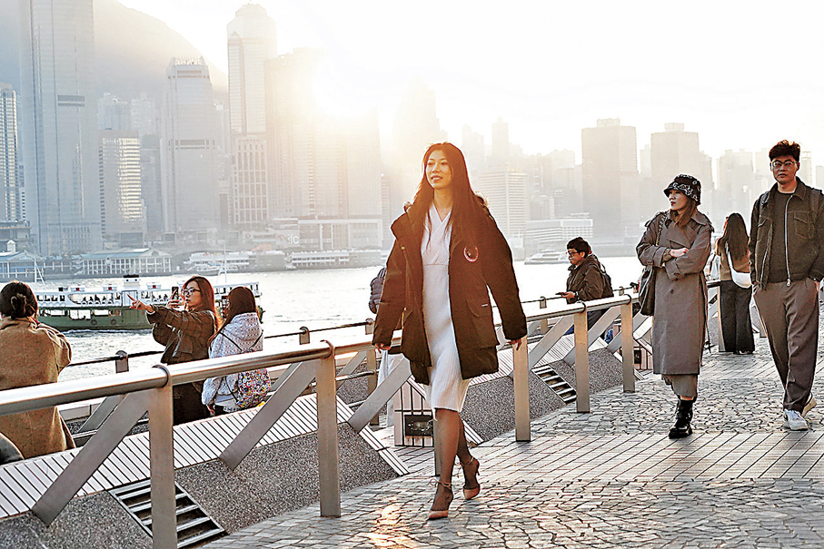 漫步海濱●晴空下，一位都市麗人穿上厚外套，輕快地步行。香港文匯報記者曾興偉  攝