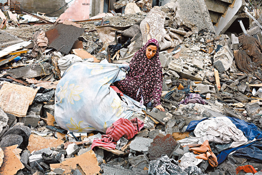 ●一名巴婦在空襲現場收拾物件。 路透社