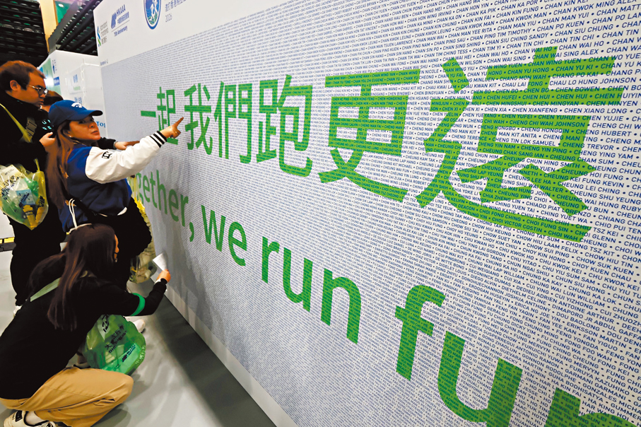 ●參加者在馬拉松博覽會跑手牆上尋找自己的名字打卡。   香港文匯報記者涂穴  攝