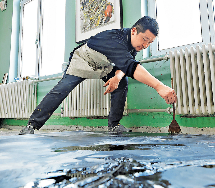 ●鄧宇手握特製竹筆創作作品。