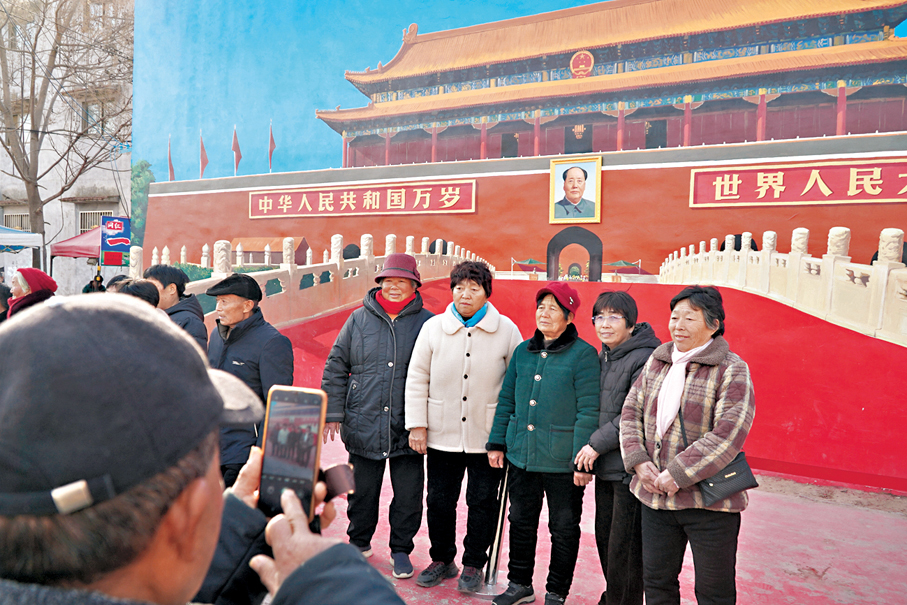 ●附近的村民和遊客在牆繪「天安門」前合影。