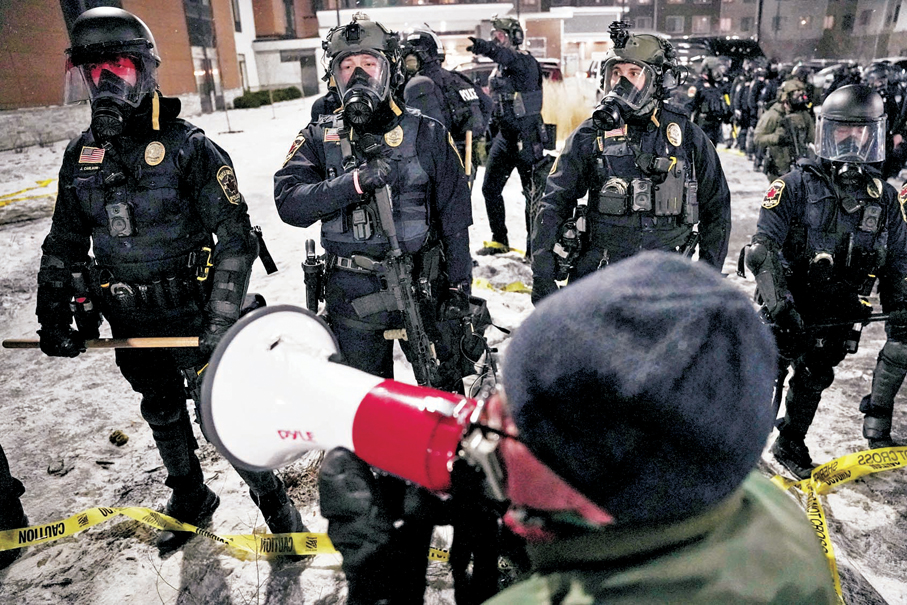 ●在明尼蘇達州楓樹林市，一名示威者在大批執法人員旁高喊口號。 路透社