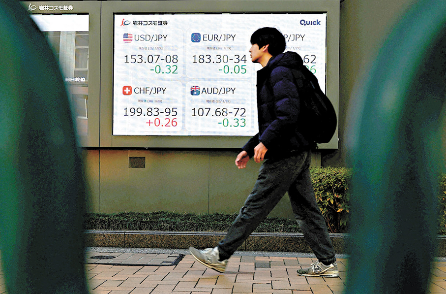 ●日民眾走過東京一間證券公司外的電子顯示屏。  路透社