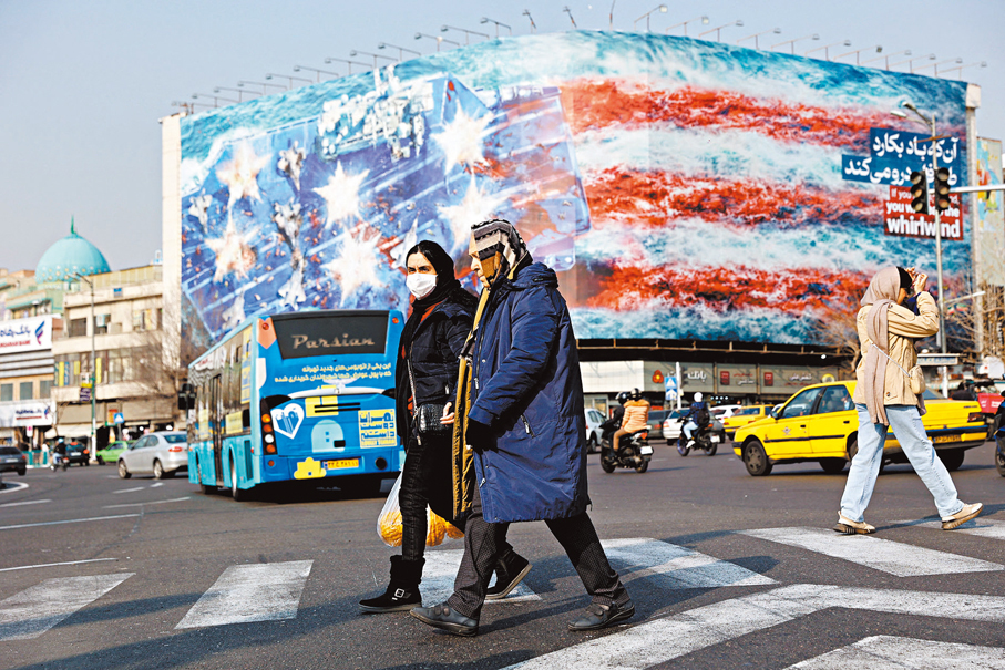 ●美國軍事威脅下，伊朗民眾行走在貼有巨幅反美海報的建築前。 路透社