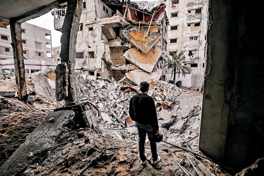 ●一名巴人在加沙城察看受損建築物。 新華社