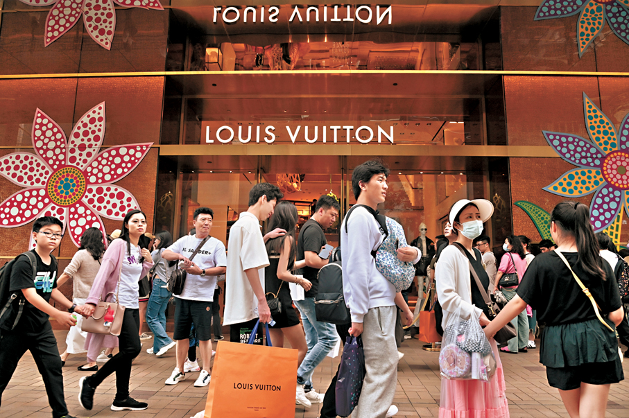 ●特區政府發言人表示，本地消費氣氛正在改善，加上訪港旅客數字持續顯著增長，會繼續對零售業務有利。圖為內地旅客到尖沙咀一帶遊覽，行經一間名店前準備購物。 資料圖片