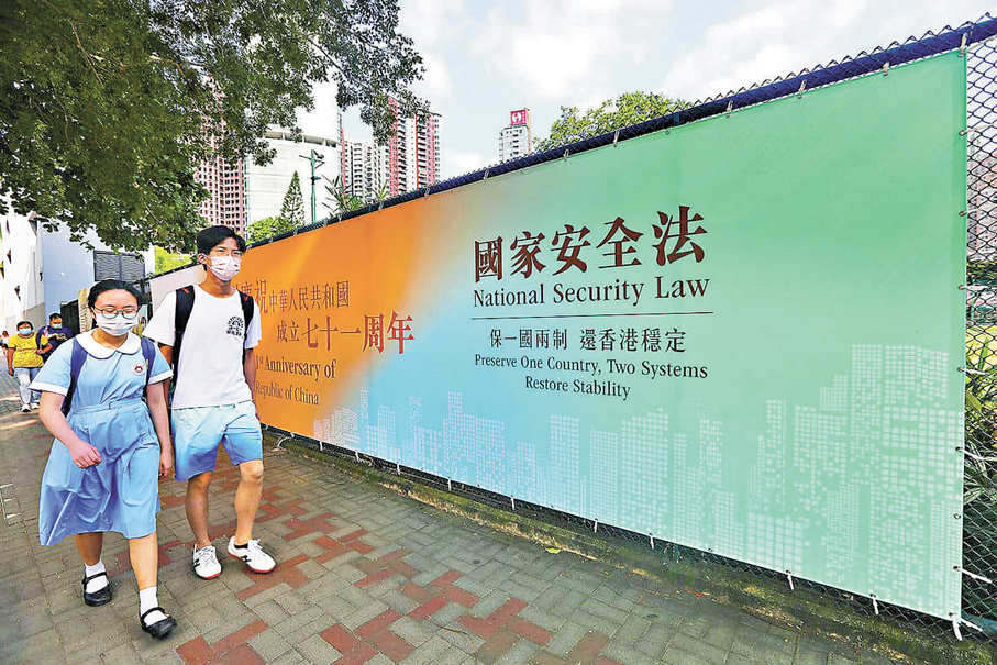 ●香港各大政團昨日均強調，黎智英案的判刑是為香港的長治久安築牢法治根基。圖為學生路經香港國安法的宣傳海報。資料圖片