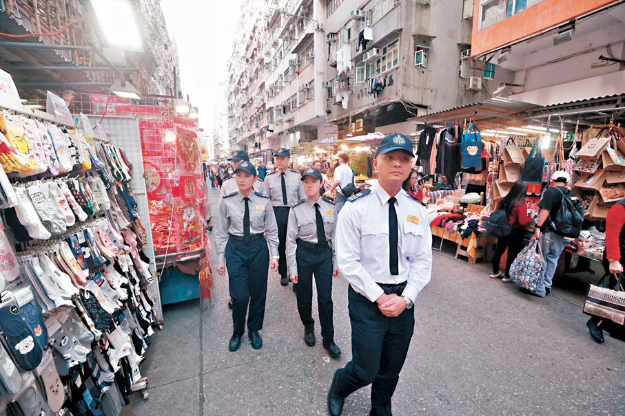 ●食環署高級小販管理主任莫詠麟（前）帶領小販管理事務隊隊員，到旺角花園街攤檔一帶巡邏。 香港文匯報記者郭木又  攝
