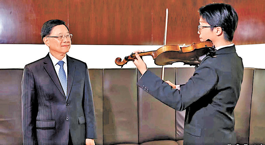 ●2025年國慶文藝晚會結束後，李家超（左）與李靖甫再相見，李靖甫專門為特首拉起一段經典小提琴樂曲《查爾達斯舞曲》並獲肯定。  李家超Fb片段截圖