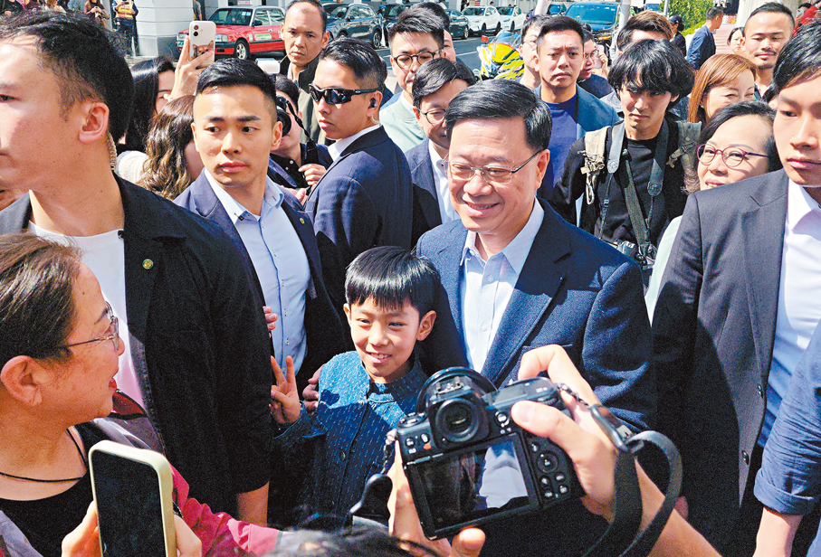 ●李家超到埗駿發花園時與市民遊客交流。 香港文匯報記者北山彥  攝