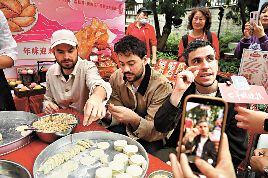 ●2月12日，外國友人在2026廣州水上花市開市現場學習製作油角。 新華社