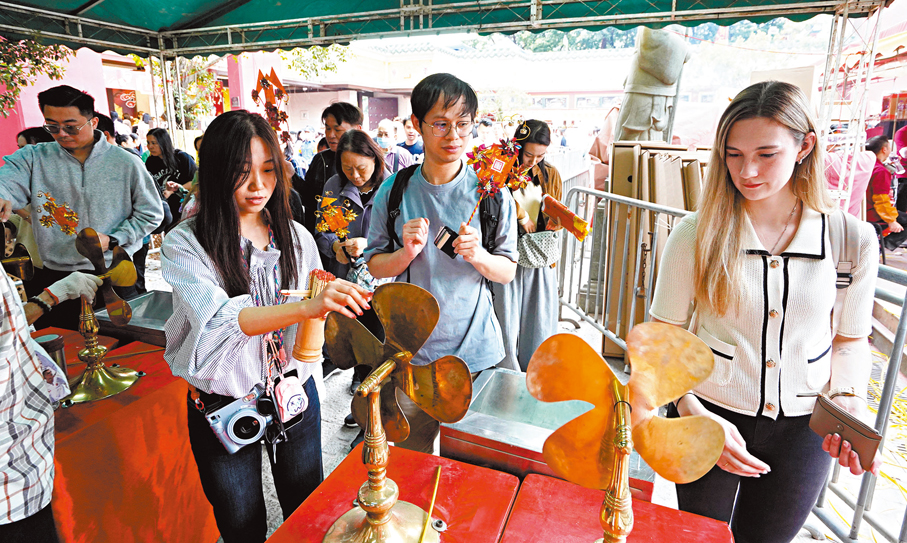●市民及旅客進入車公廟祈福，轉動風車「除衰運」。  香港文匯報記者曾興偉  攝