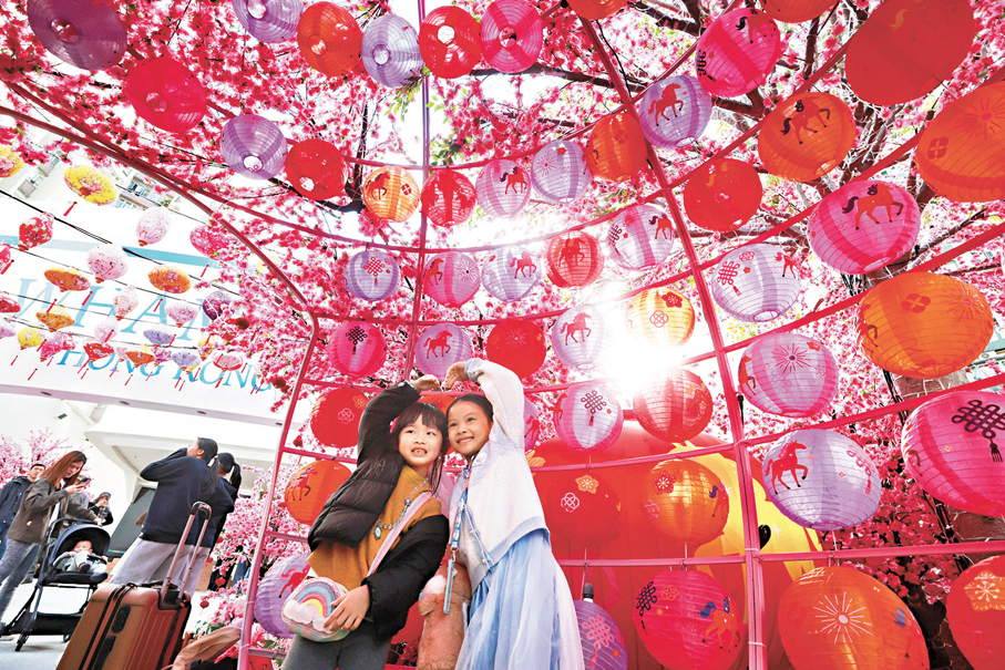 兩個小女孩擺出心形圖案合照，紅彤彤的燈籠襯托下，熱情似蘋果紅酒般洋溢四周。 香港文匯報記者郭木又  攝