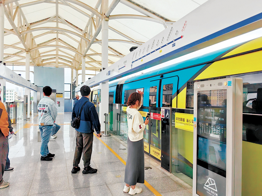 ●比亞迪「雲巴」作為無人駕駛高架電動膠輪軌道交通系統，遊客爭先乘坐體驗。   香港文匯報記者郭若溪  攝