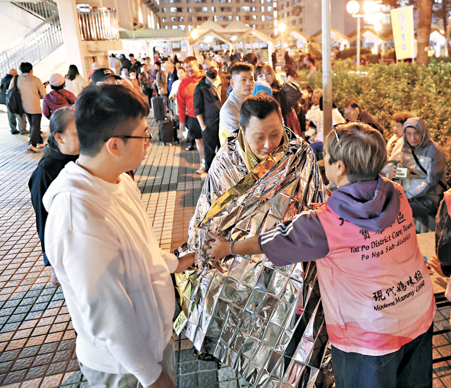 ●大埔宏福苑火災善後支援中，超過一千九百位來自全港的關愛隊隊員及義工積極參與。圖為火災當晚關愛隊隊員為居民提供物資保暖。 資料圖片