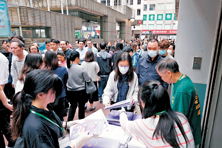 ●市民輪候領取財政預算案演辭文本和摘要單張。 香港文匯報記者黃艾力  攝