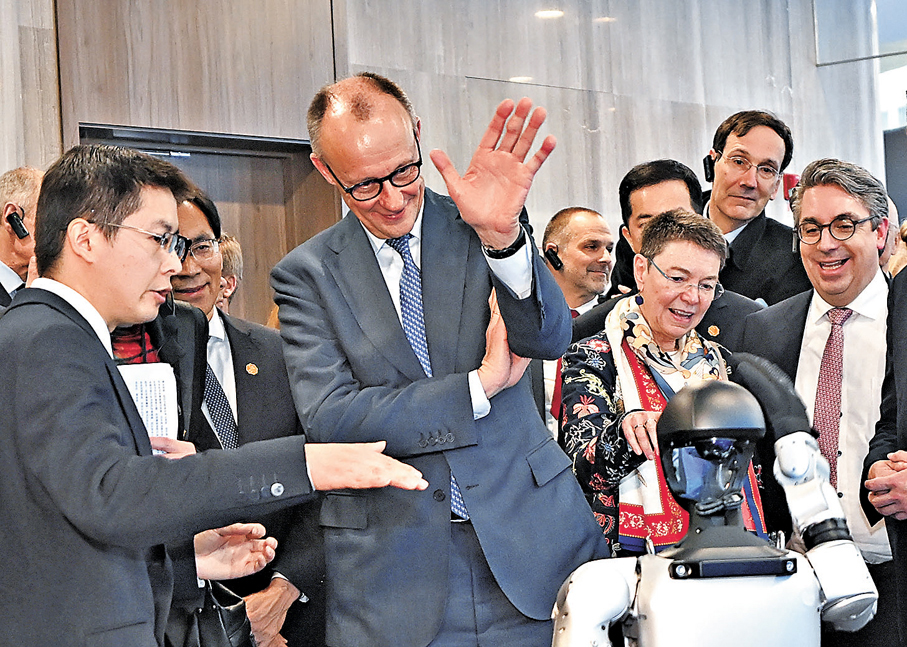 ●德國總理默茨和人形機器人招手互動。 中新社