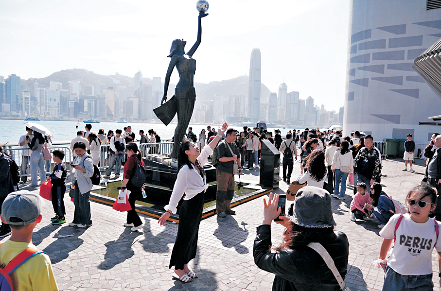 年廿七，在尖沙咀星光大道，一名遊客模仿雕像的姿勢拍照，似模似樣。 香港文匯報記者曾興偉 攝