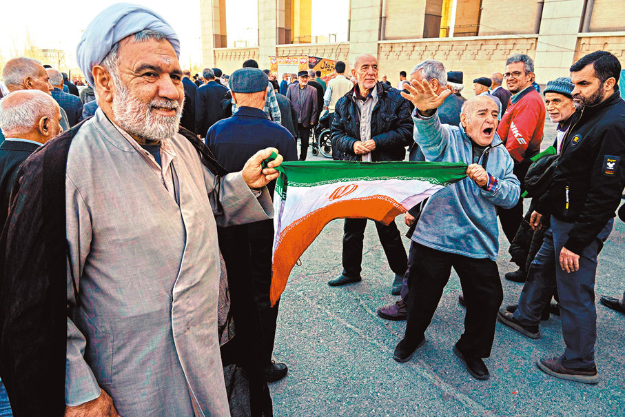 ●伊朗信眾在德黑蘭手持國旗高喊口號。美聯社