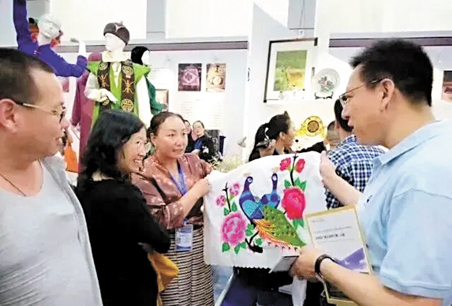 ●更藏措帶領她的「娘子軍」成為青海黃南州的青繡領頭雁，帶領鄉親們共同富裕。圖為更藏措（中）在展會上推廣熱貢刺繡產品。