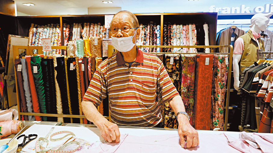 旗袍師傅關國權埋首於一塊塊綢緞之間，佝僂的背脊與花白的頭髮，訴說着他超過半世紀的專注與執着。   