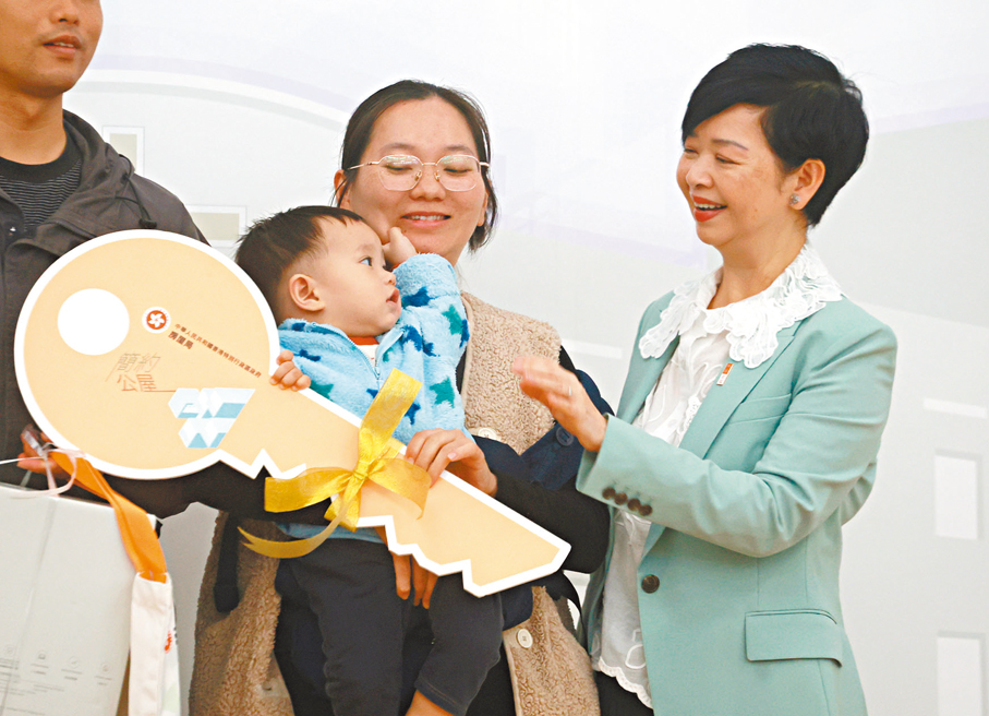 ●何永賢派發大鑰匙及入伙禮物給居民，並與小朋友互動。  香港文匯報記者郭木又  攝