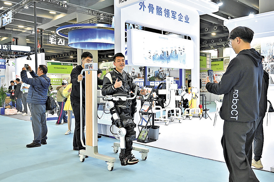 ●有委員認為，人負責決策、創新和複雜問題處理，機器負責執行、重複和精準操作。圖為參觀者在廣州一個家用醫療展體驗外骨骼機器人。 中新社