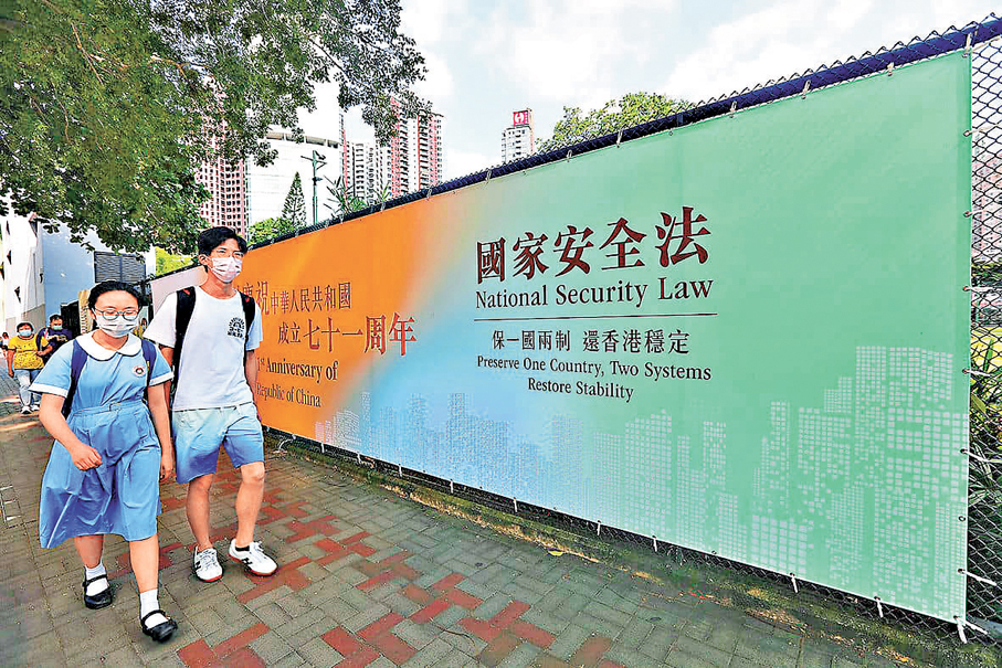 ●特區政府教育局昨日向全港官津及直資中小學發通函，通知各校長和教師國安白皮書學與教資源事宜。圖為學生路經香港國安法宣傳橫額。 資料圖片