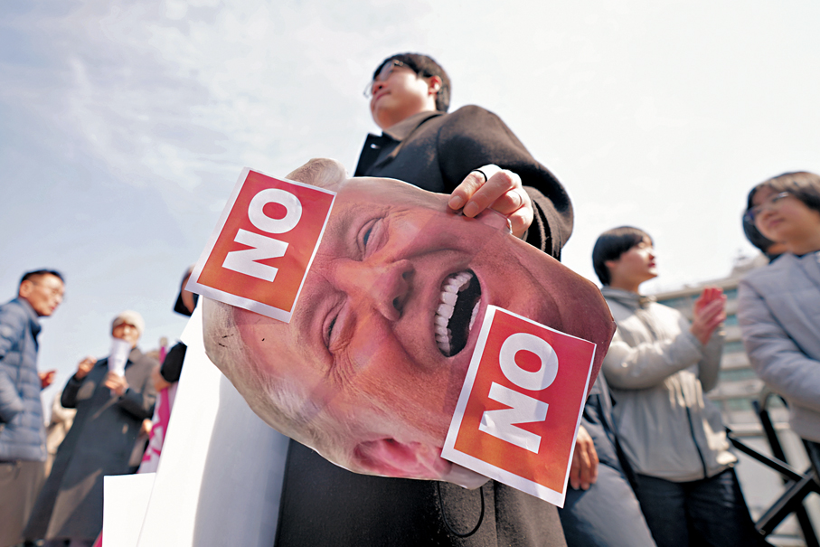 ●在美國駐韓大使館外，一名男子手持特朗普畫像，反對美國要求別國替霍爾木茲護航。  美聯社