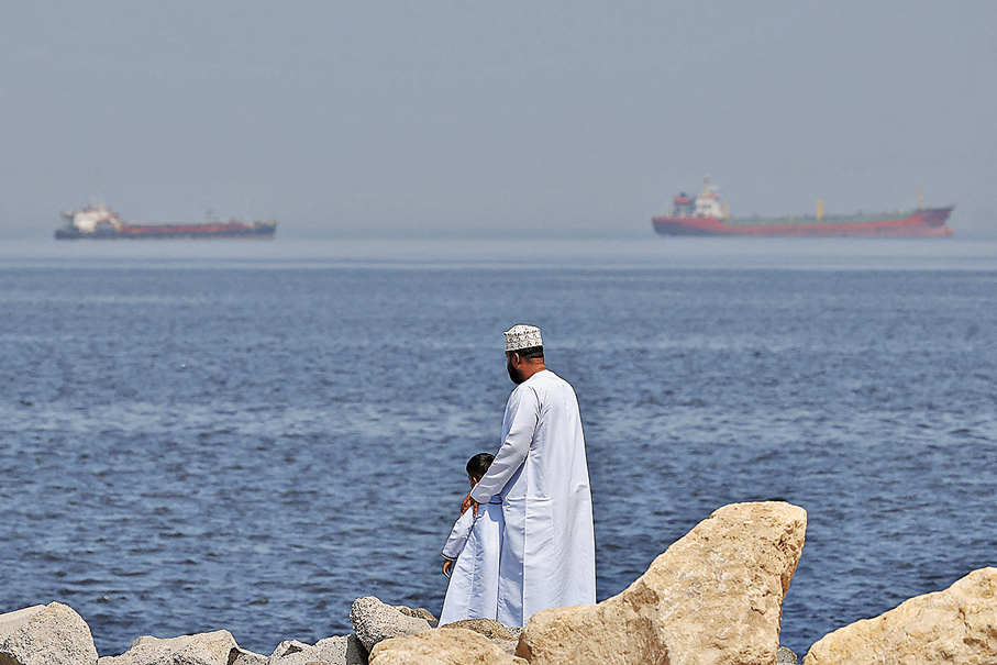 ●在阿曼的蘇丹卡布斯港附近，一名男子和一名兒童站在岸邊。 路透社