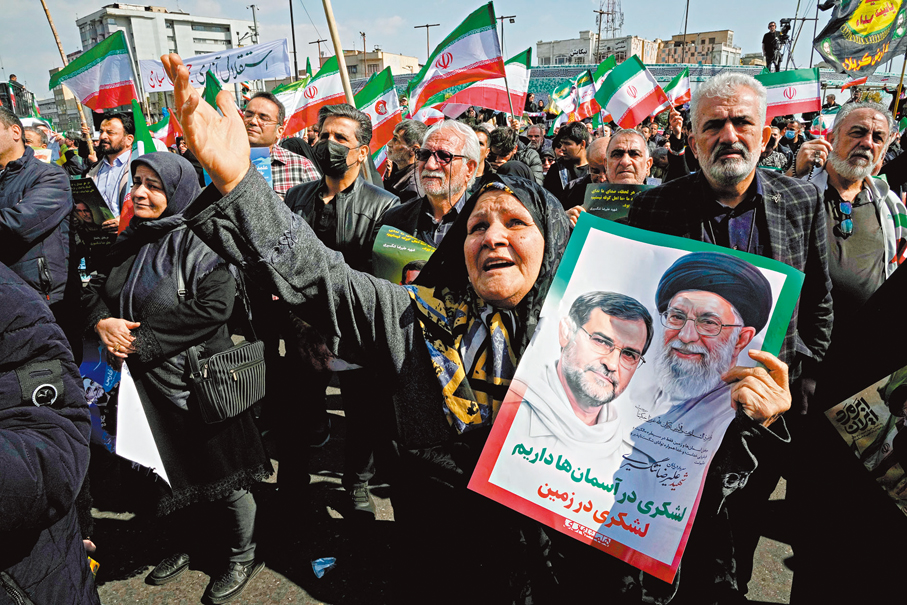 ●德黑蘭民眾手持國旗及哈梅內伊海報，參加反美遊行。  美聯社