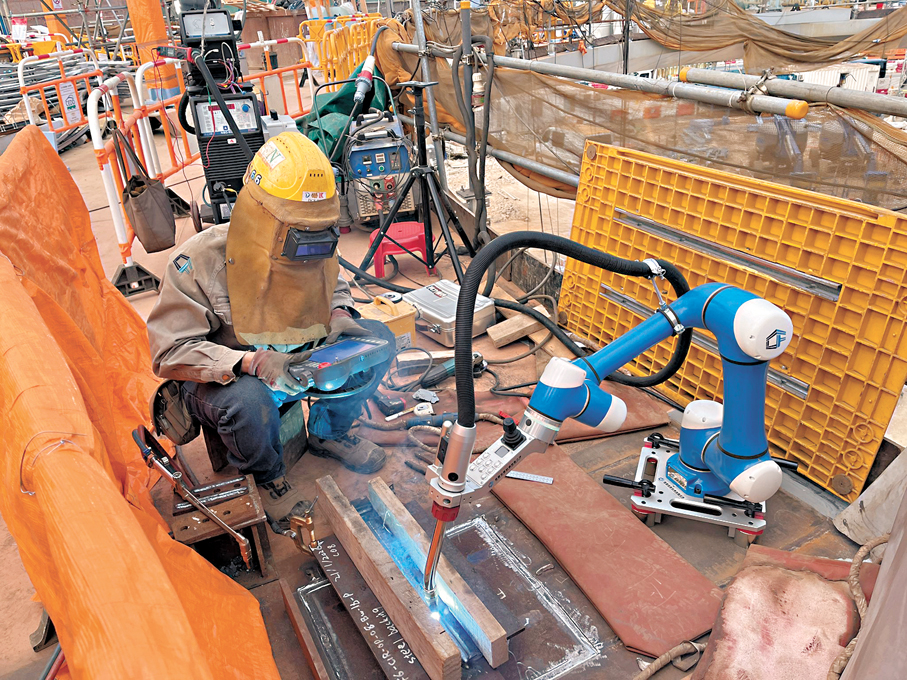 ●建造業引入新科技，圖為建造業議會焊接技能大使向參與世界技能大賽的選手，示範使用智能機械人協助工作。  建造業議會Fb圖片