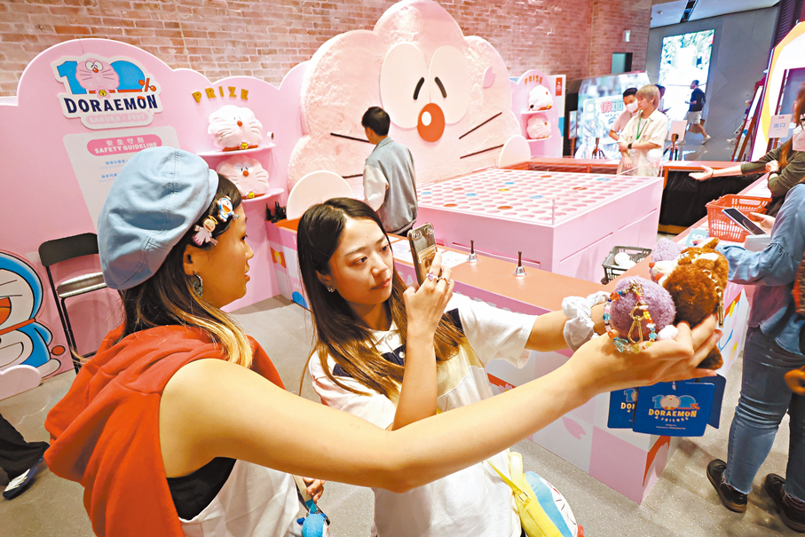 ●少女參加多啦A夢展，用手機攝下可愛的展品。 香港文匯報記者涂穴  攝