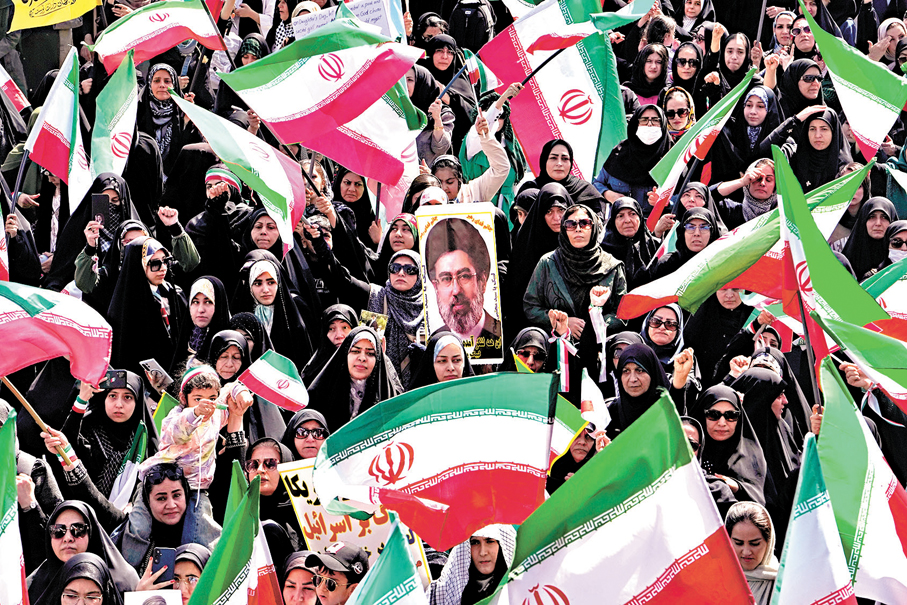 ●德黑蘭婦女手持伊朗國旗和最高領袖穆傑塔巴畫像遊行。  美聯社